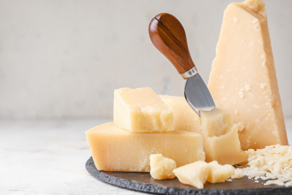 Slate plate with tasty Parmesan cheese on light background.