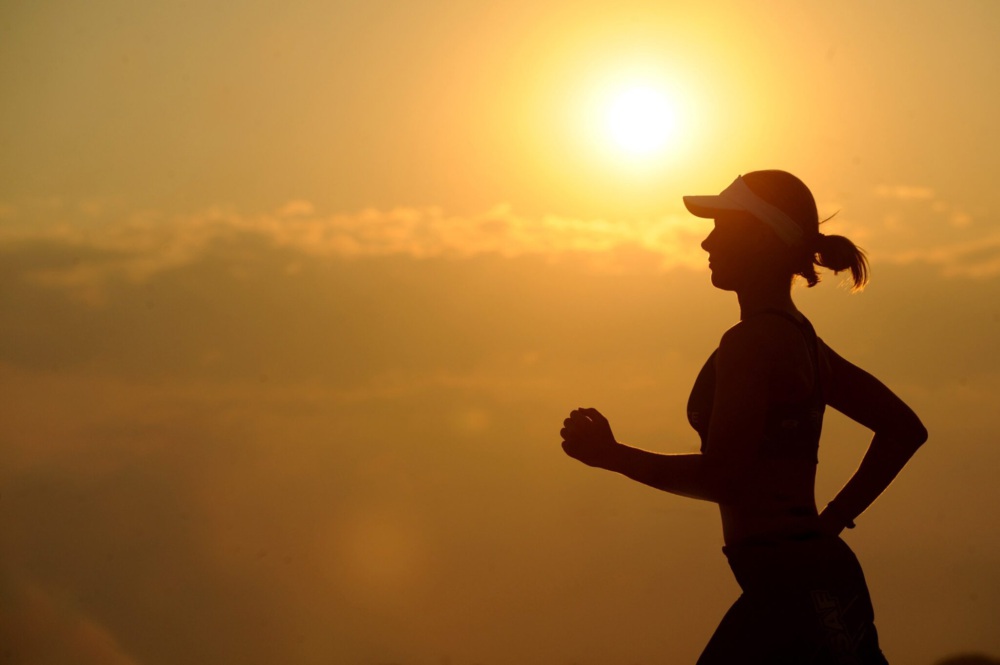 A woman running with the sun setting behind her