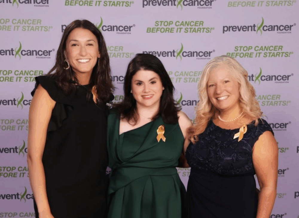 Image of three woman in fancy dresses standing together at an event.