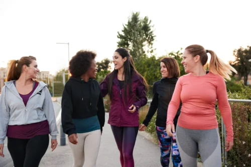 Three-quarter length view of a group of women walking and talking. They are wearing sportswear.