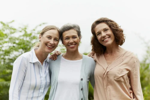 Three happy women in their 40s and 50s standing in park