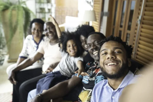 Young man taking a selfie of his family, including a child and seniors.