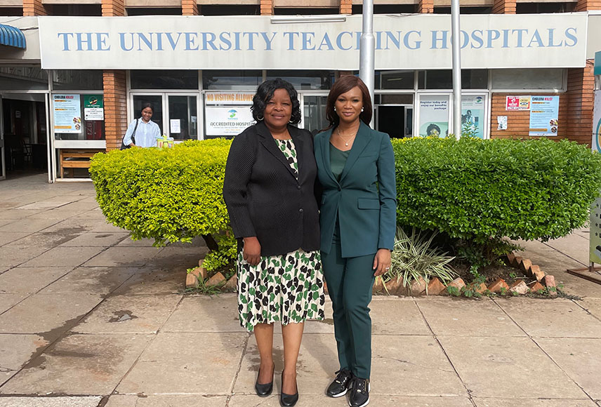 Two African female doctors stand outside of a teaching hospital in Zambia.