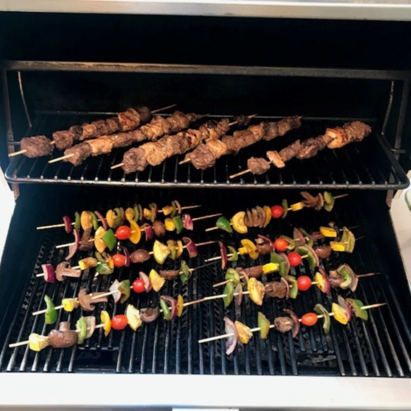 Vegetables and meat shish kabobs cooking on the grill.