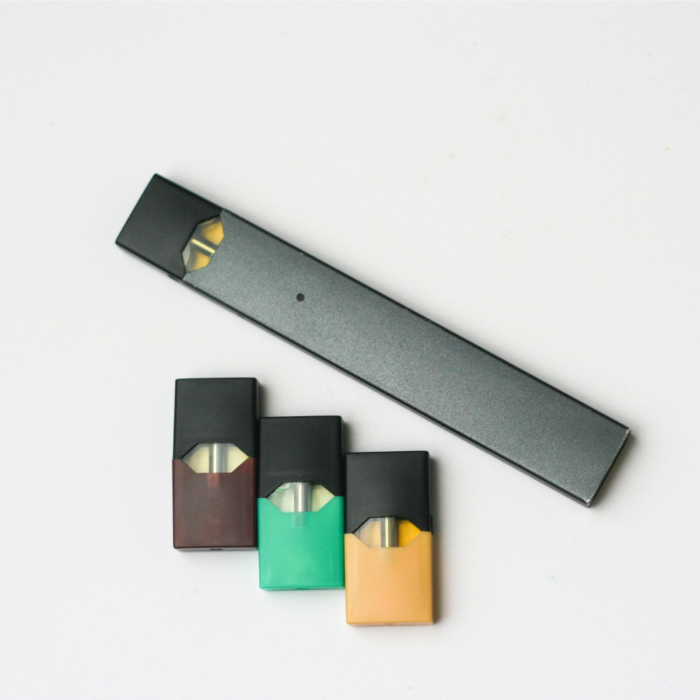 A gray background with a juul and three pods.