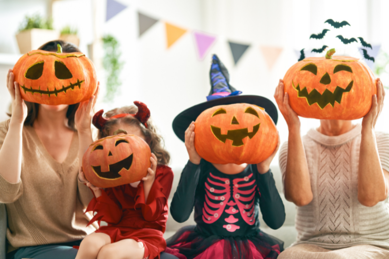 A family of four put jack o'lanterns in front of their faces