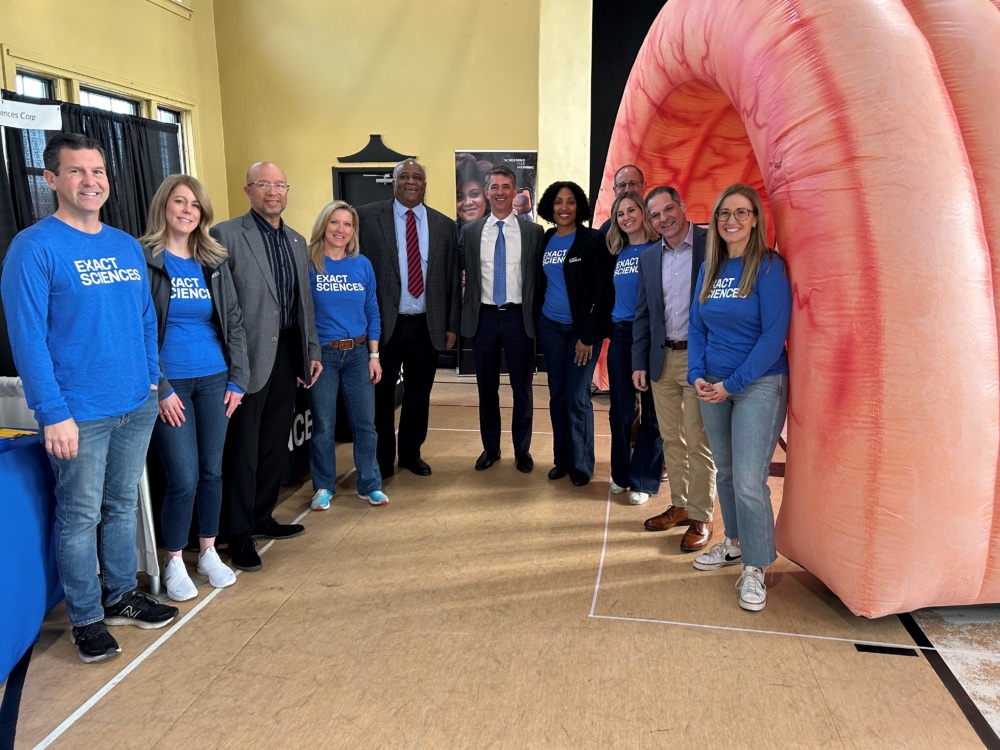 People in Exact Sciences tee shirts pose at a health fair