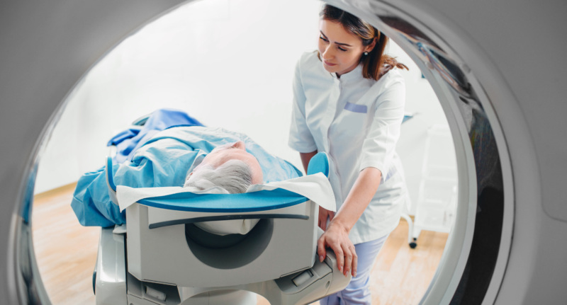 A patient is lying down in a CT scan and a doctor looks on