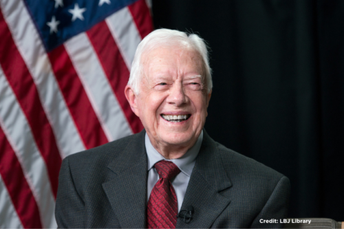 Jimmy Carter smiles in front of the American flag. Credit: LBJ Library