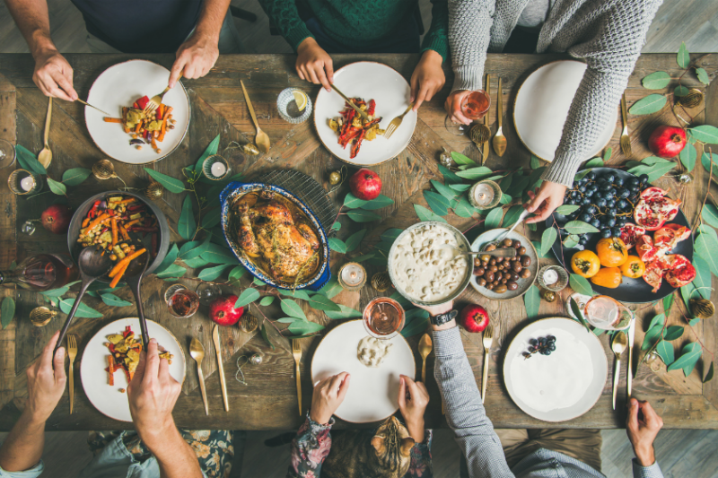 An aerial shot of hands reaching toward festive foods on a dinner table