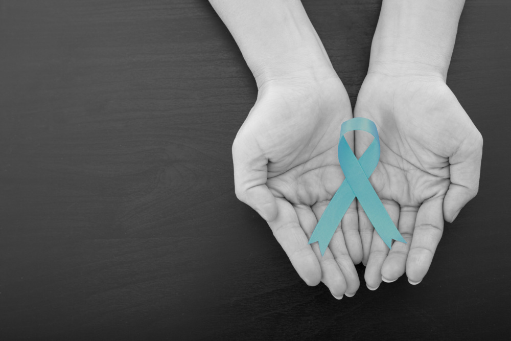 Two hands hold a teal ribbon to represent cervical cancer