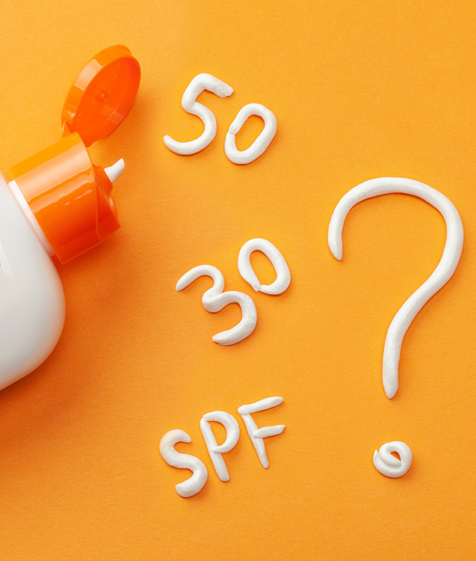 Sunscreen on orange background. Plastic bottle of sun protection and white cream in the form of question mark and numbers SPF. How to choose a sunscreen.