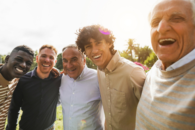 Five men stand together smiling with arms across each others' shoulders.
