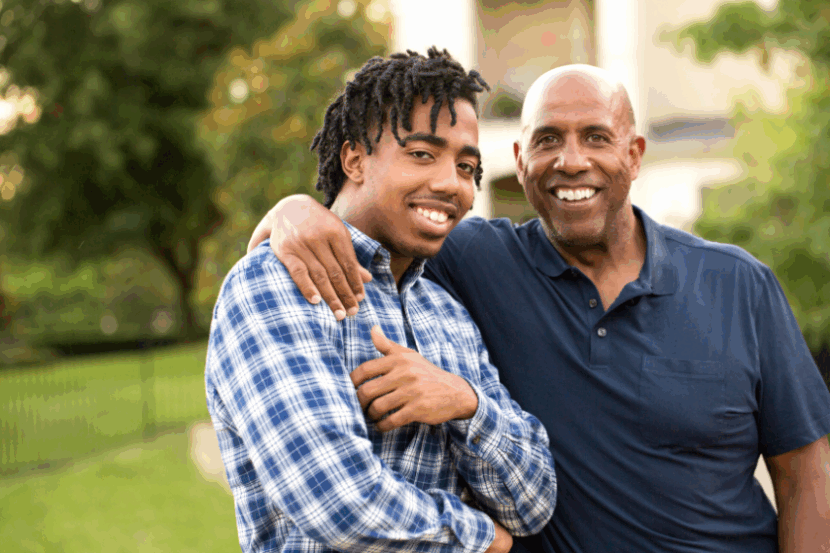 A father with his arm around his young adult son.