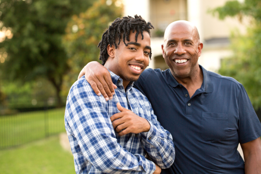 A father with his arm around his young adult son.