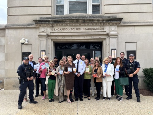 Spouses of US Congresspeople stand outside the US Capitol Police headquarters, posing for a group photo.