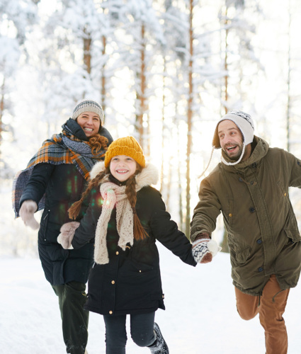 A family of three bundled up and playing in the snow.