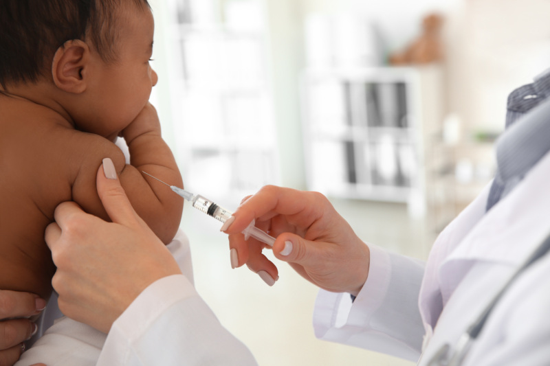 Pediatrician giving little baby an injection in clinic.