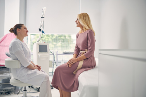 Smiling female doctor sitting while listening to her patient in doctor room.