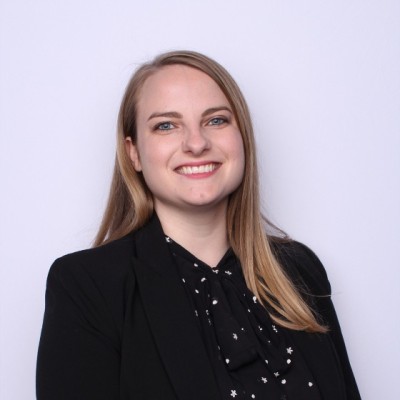Headshot of a blonde woman in a black blouse and jacket.
