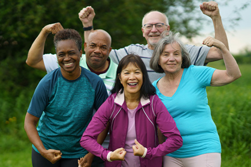 A diverse group of older adults showing their strength after a workout in the park.
