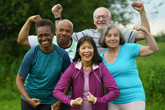 A diverse group of older adults showing their strength after a workout in the park.