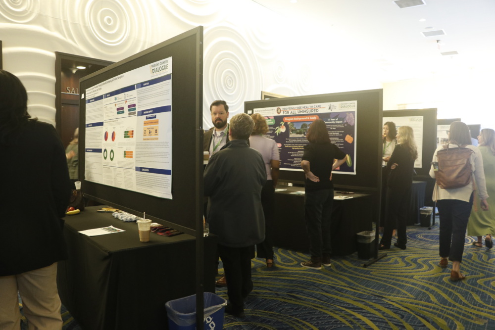 A group of presenters stand at their posters, explaining information.