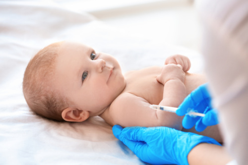 Doctor vaccinating baby in clinic.