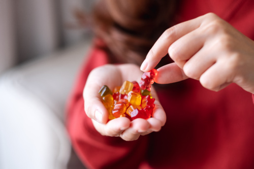 Woman in a red shirt picking up a gummy bear.