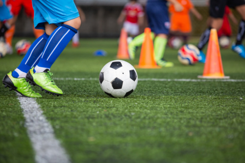 Boy playing soccer on turf field.